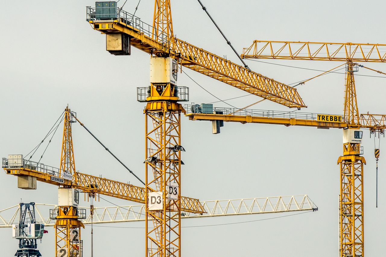 The Art of Drawing Readers In: Your attractive post title goes here Cluster of yellow tower cranes at a construction site with a gloomy sky background.